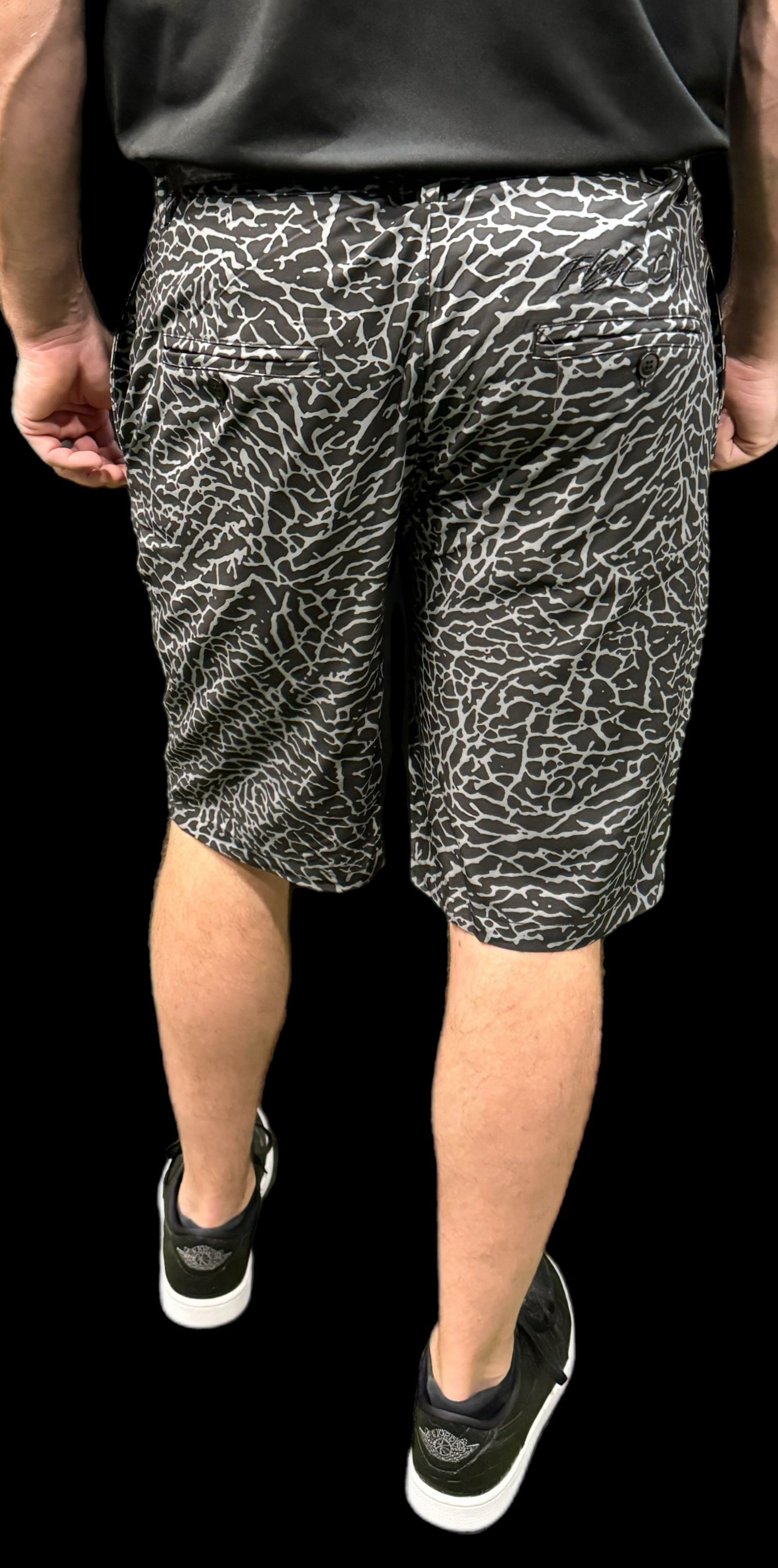 Person wearing black and white patterned shorts on a black background